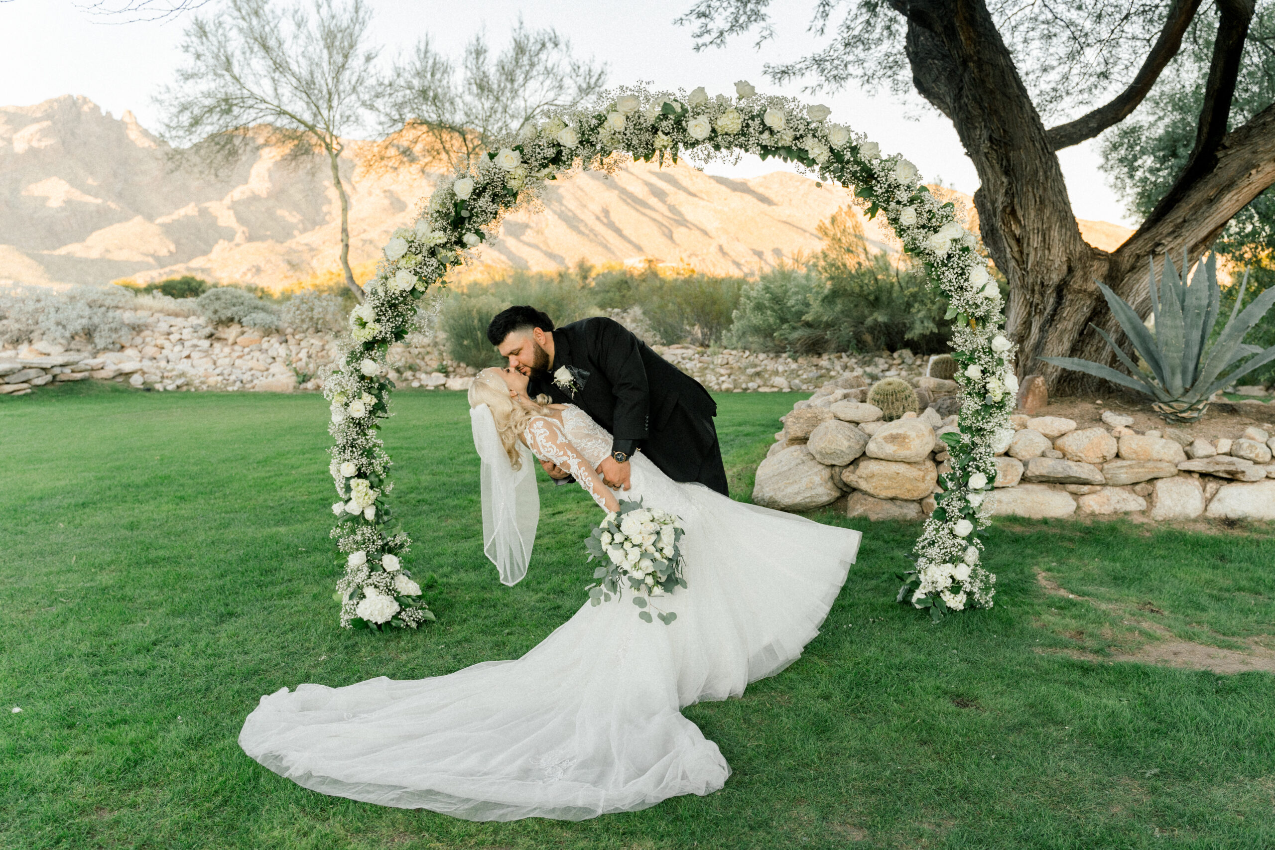 Wedding at Westin La Paloma in Tucson, AZ. Bride and groom kiss in front of a rose arch. Ruby Sandoval Photography.