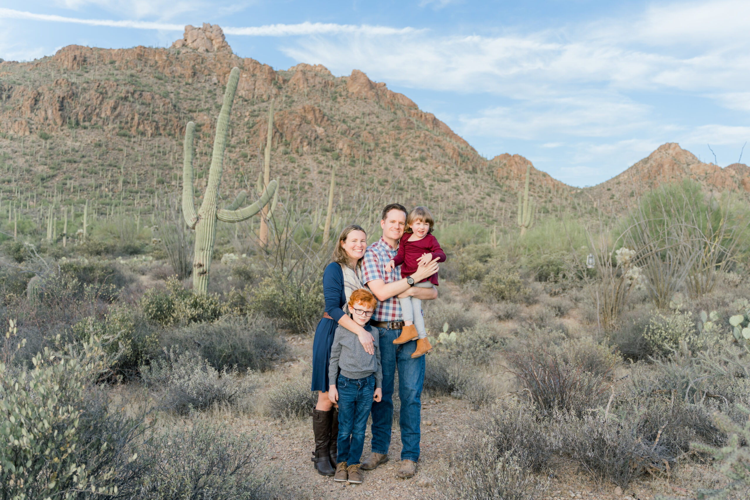 family poses in front of mountains during a Family session at Gates Pass in Tucson, AZ. Ruby Sandoval Photography