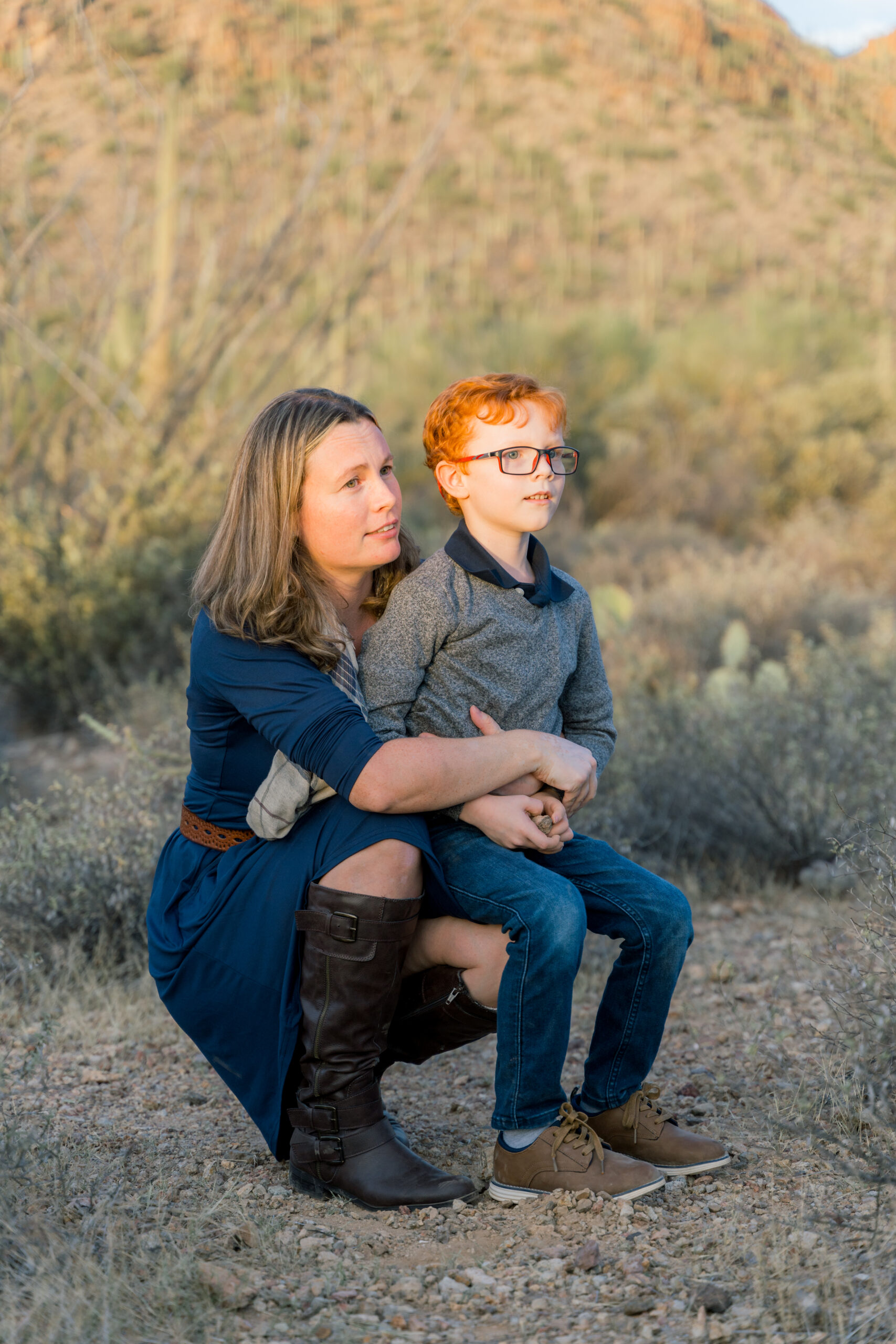 Mother hugs son in front of mountains during a family session at Gates Pass in Tucson, AZ. Ruby Sandoval Photography
