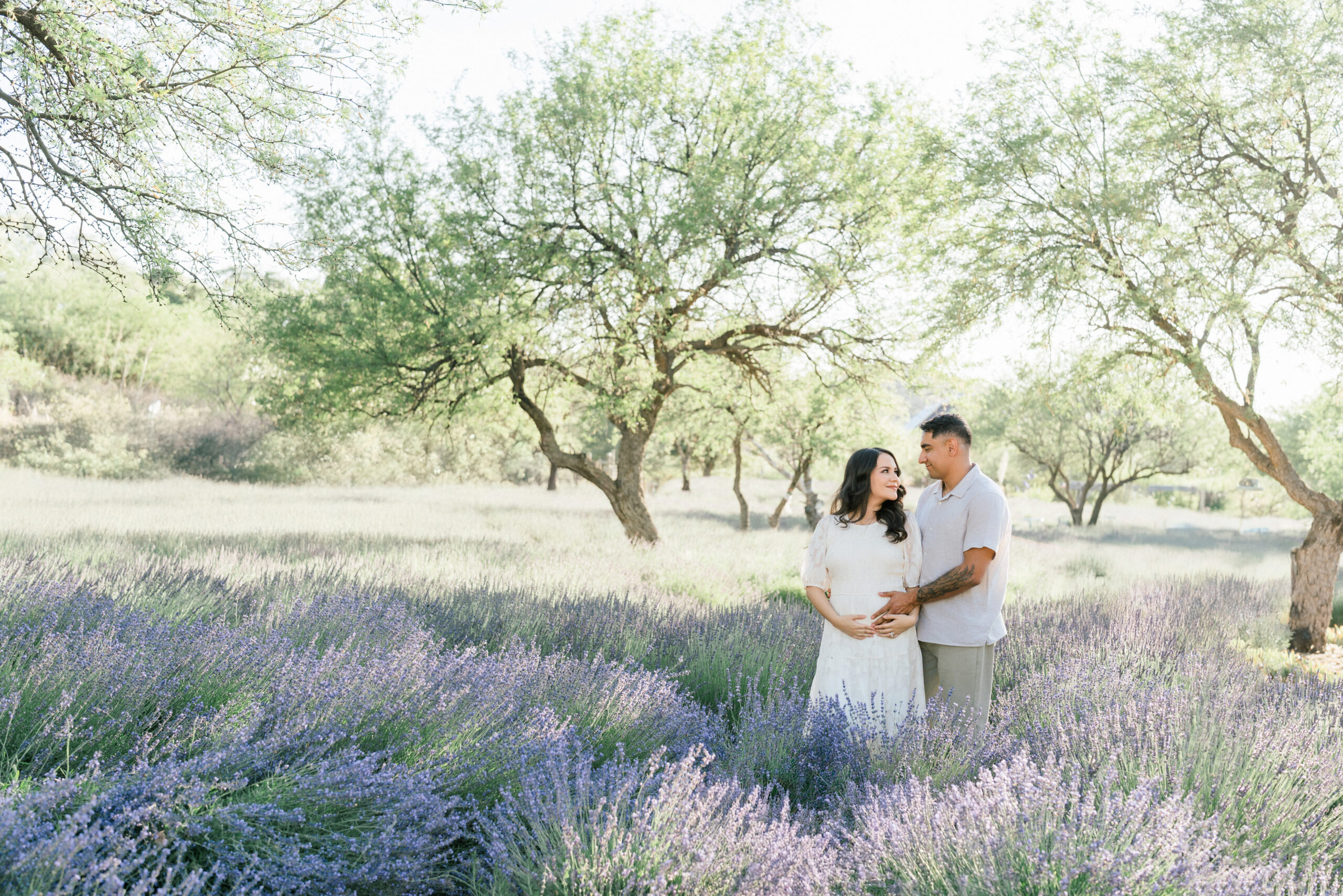 Couple in a field of lavender wearing neutral spring clothes during a maternity session in Arizona.